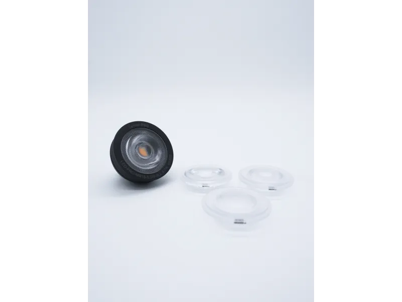 Black LED light bulb and three clear lens covers on a white background in a minimal setup
