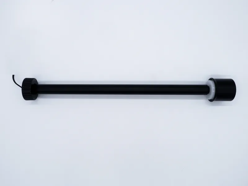 Black cylindrical electronic device with a cord and two distinct end caps, placed on a white background