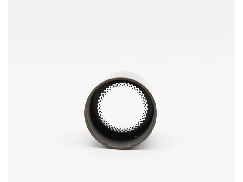 Top view of a coffee cup lid with a circular perforated white insert on a plain background