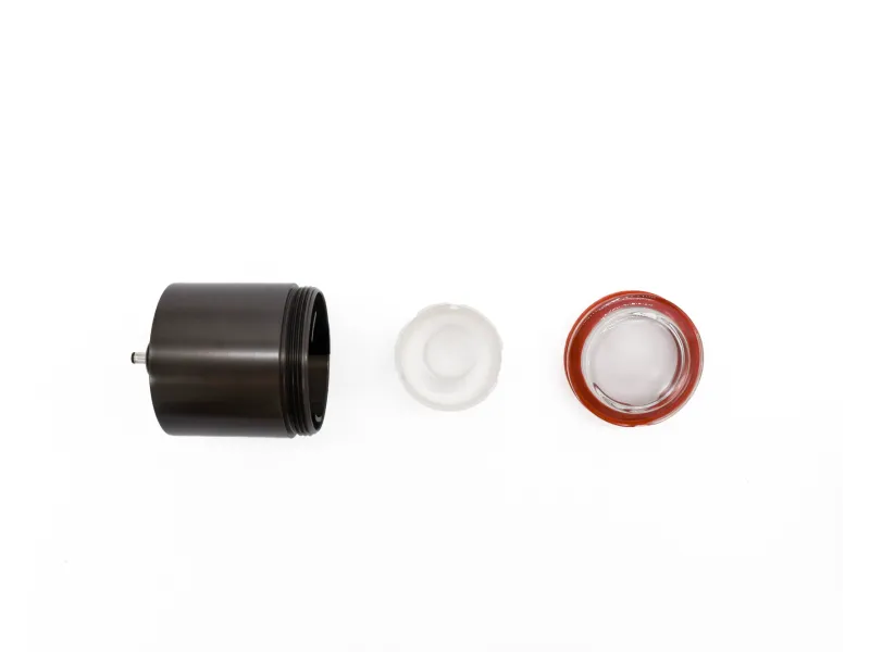 Disassembled camera lens components including black metal barrel, translucent white ring, and glass element on white background