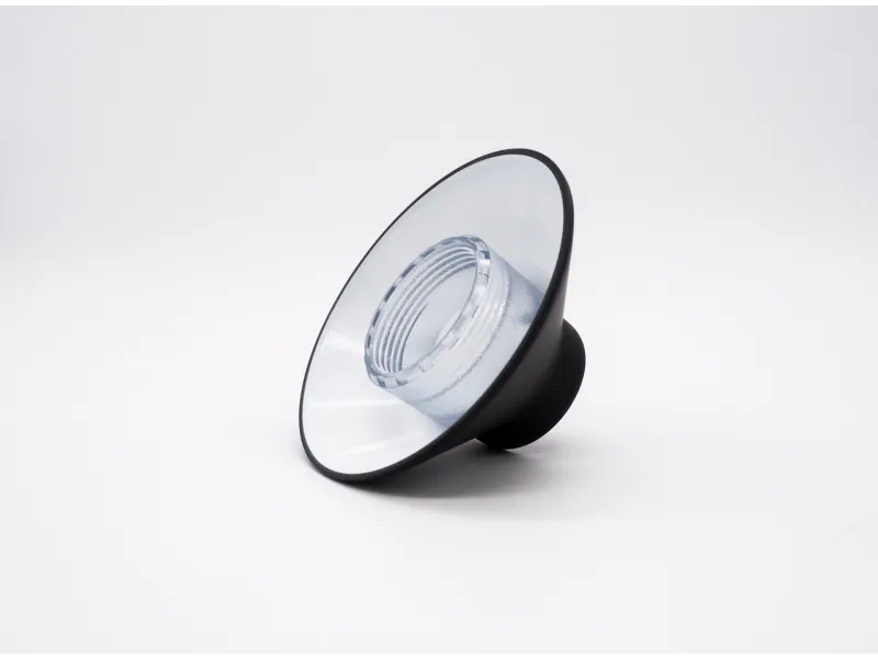 Black and transparent plastic lamp reflector with cone shape lying on white background.