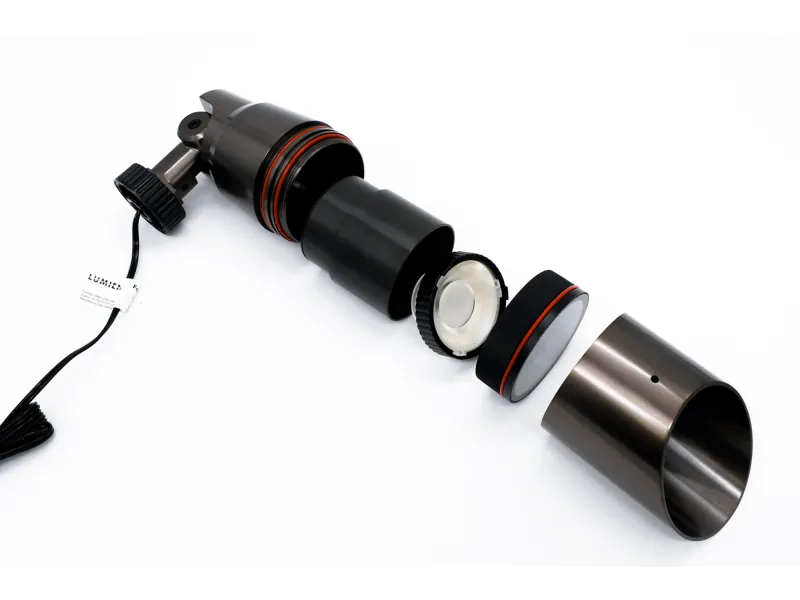 Disassembled black and silver metal device with red rings, cable, and multiple cylindrical components on white background