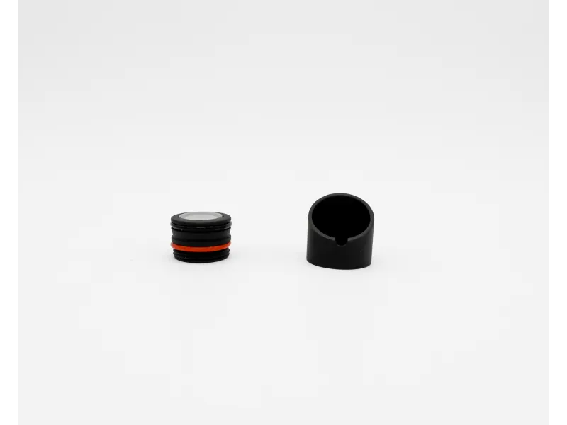 Two small black mechanical parts on a white background, one with red ring and threads, one hollow with notch.