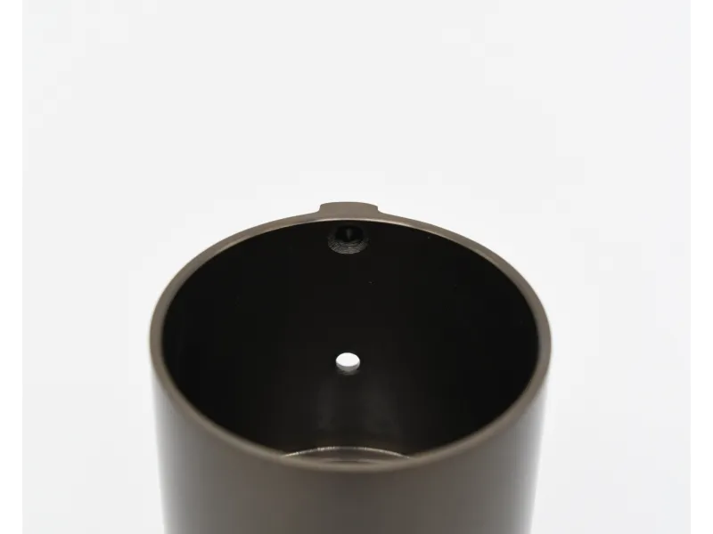 Close-up of a cylindrical black metal object with a small central hole on a white background.