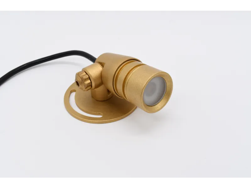 Compact brass outdoor spotlight fixture with adjustable mount and black electrical cable on white background
