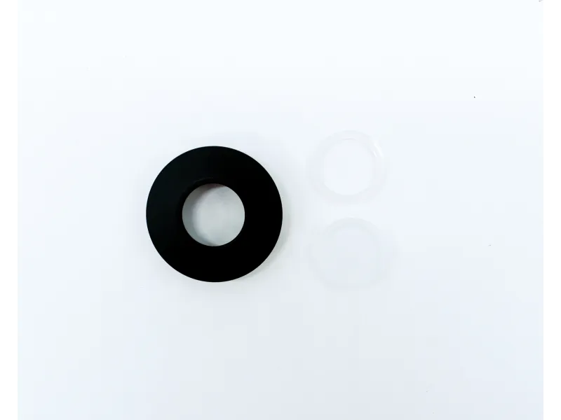 Black circular ring with two translucent washers placed on a white surface, minimalistic composition.