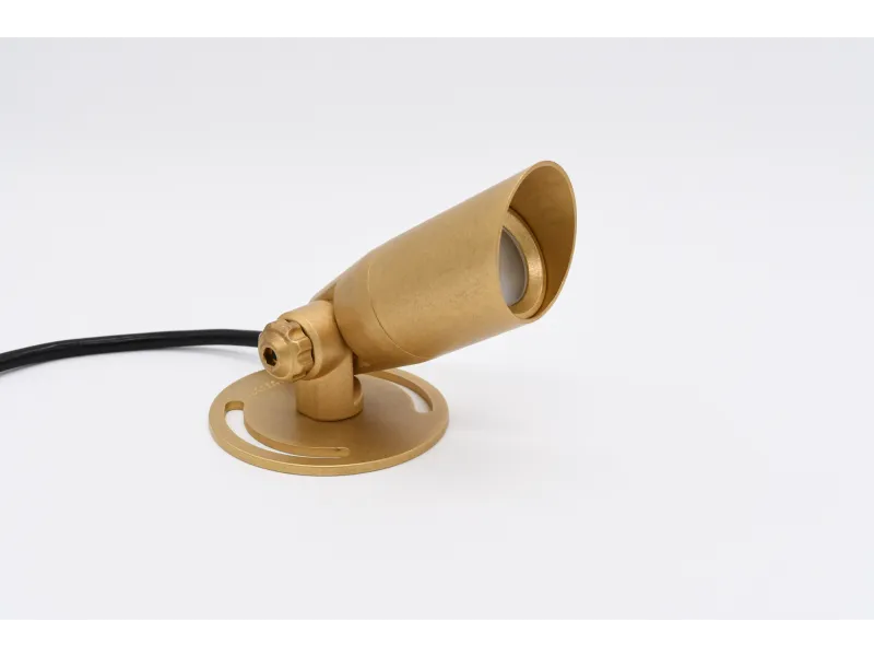 Compact gold-colored adjustable spotlight with round base and black power cord on white background