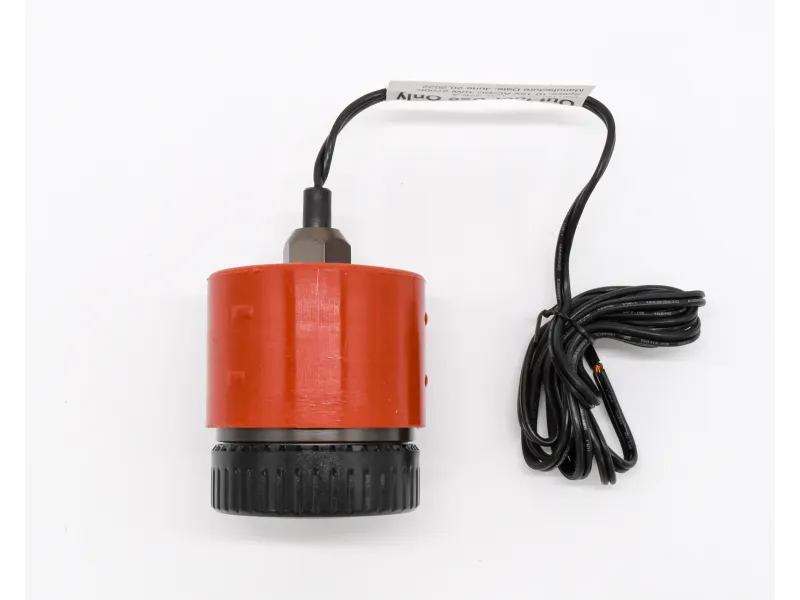 Red and black cylindrical sensor device with attached black cable coiled beside it on white background