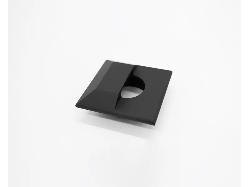Black square plastic cable clip with a circular hole and angled design on a white background.