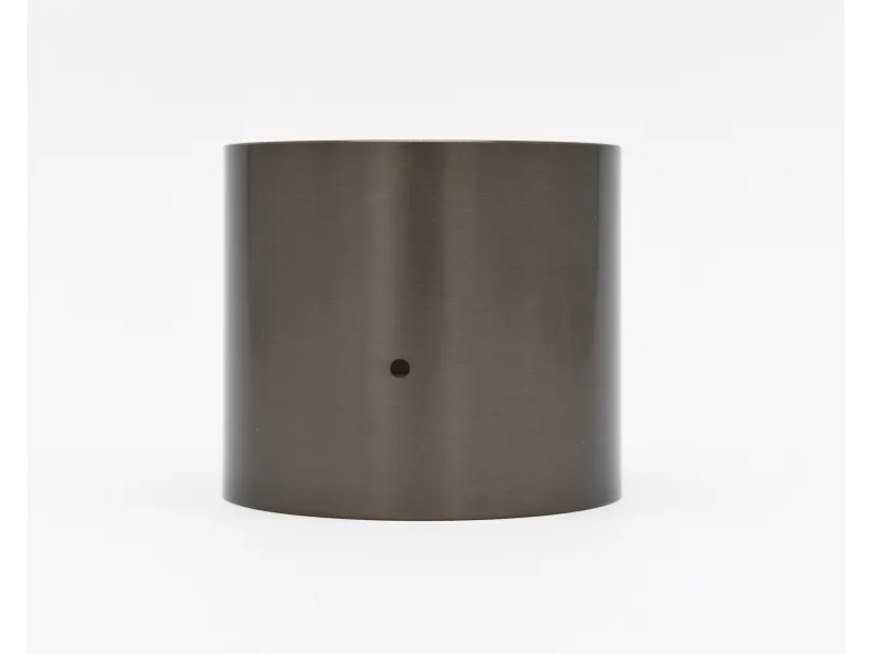 Brushed metal cylindrical object with a small central hole on a white background