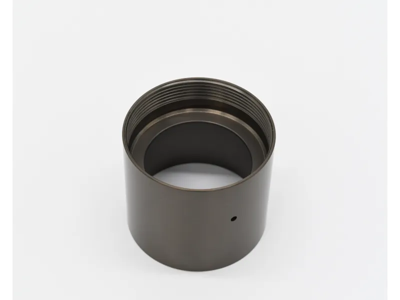 Dark metallic cylindrical component with internal threading and small side hole on a white background.