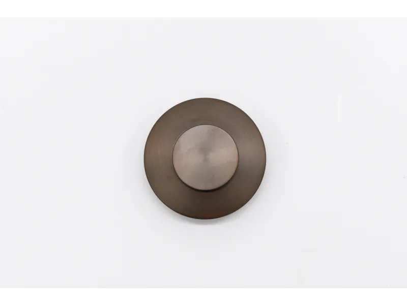 Round bronze metal doorbell button on a white background, centered in the image.