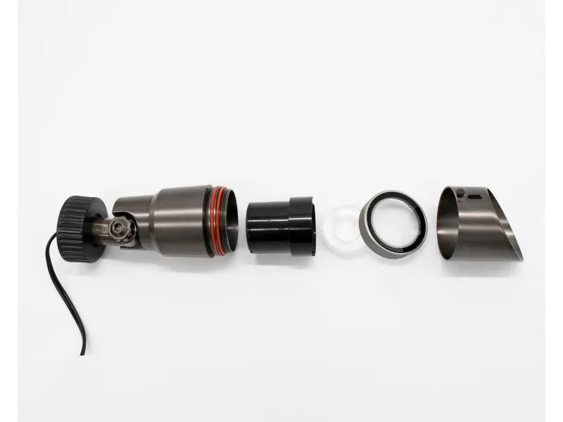 Disassembled black metal and plastic cylindrical device with seals and mesh filter parts on a white background