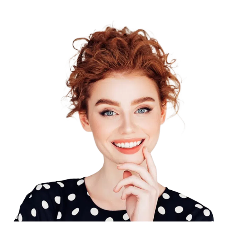 Smiling young woman with curly red hair and blue eyes wearing a black dress with white polka dots.