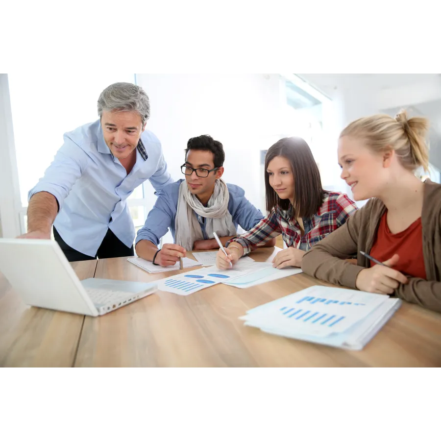 a group of people sitting at a table looking at a laptop