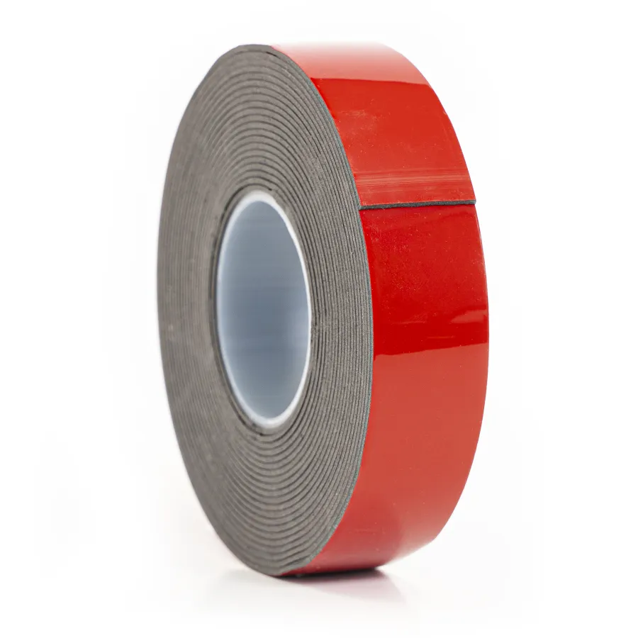 Roll of black foam tape with red adhesive backing on a white background close-up