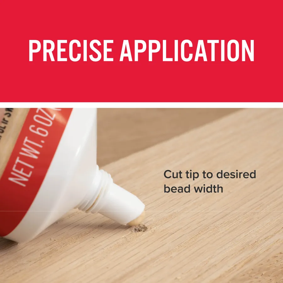 Close-up of adhesive tube applying precise bead on wooden surface with red label and white nozzle.
