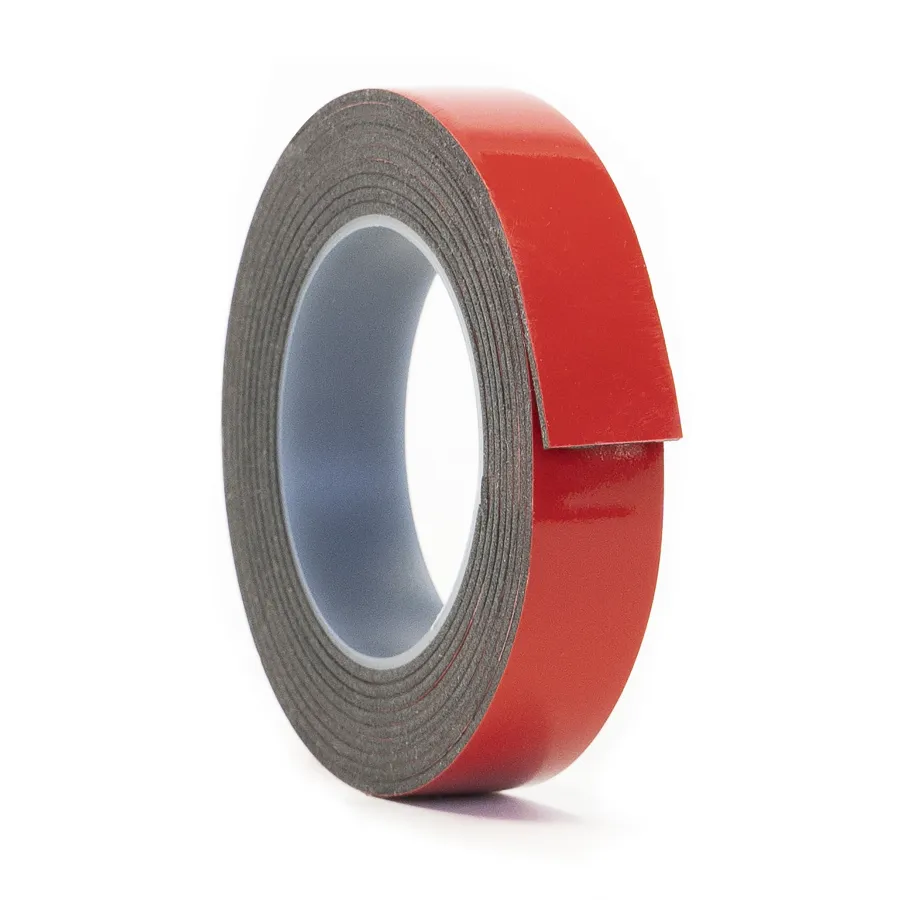 Roll of red double-sided adhesive foam tape with protective backing partially peeled off on white background