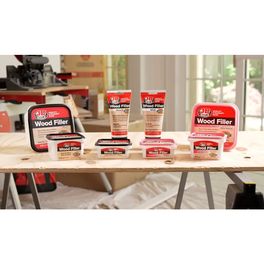 Variety of JB Weld Wood Filler products displayed on a wooden plank in a workshop setting.