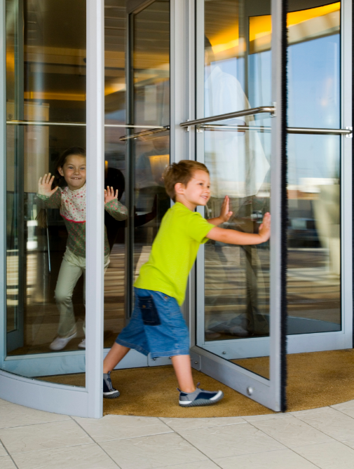 Kids walking through a revolving door.