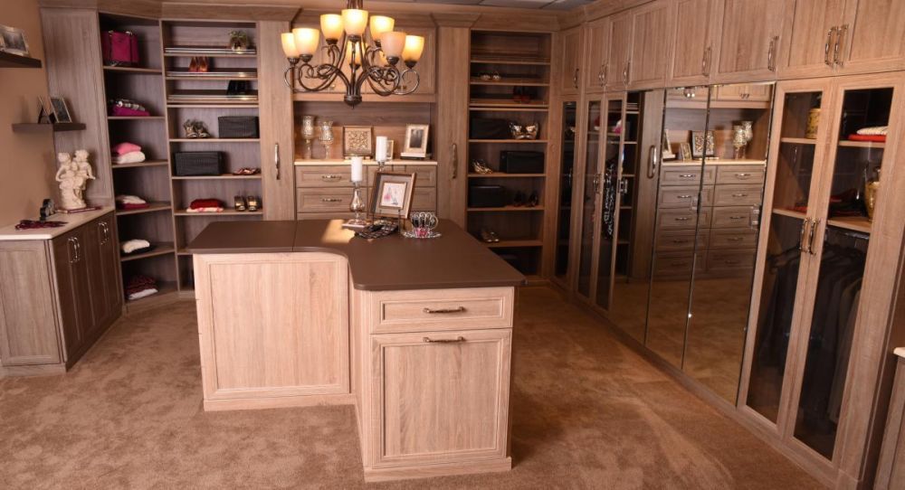 A beautiful, large master closet system has wrap around storage and a large island in the middle with extra storage.