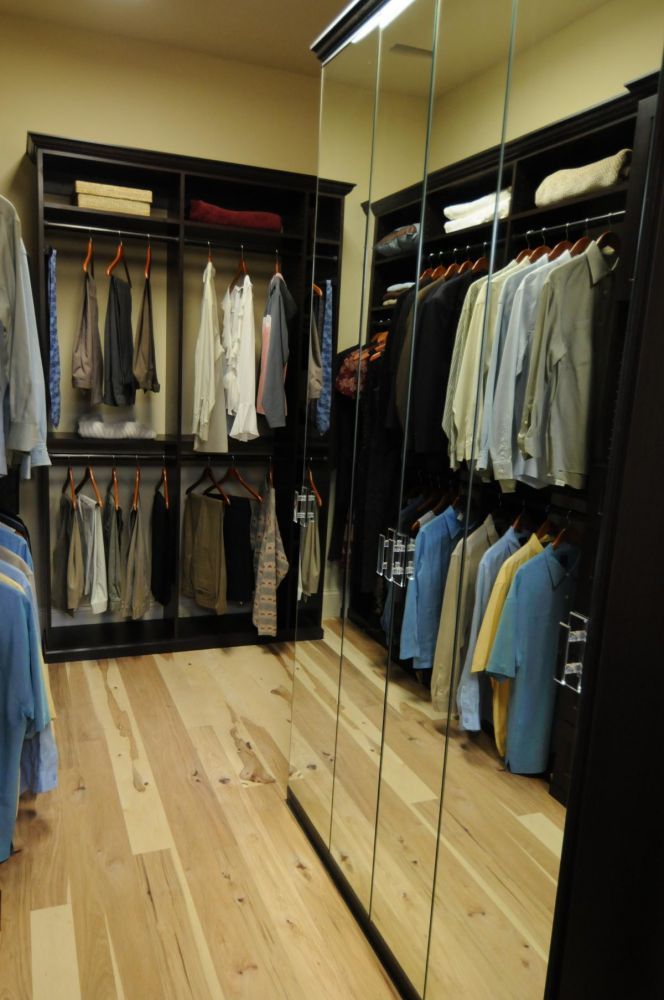 An elegant master closet system with mirrored storage cabinets and simple hanging racks.
