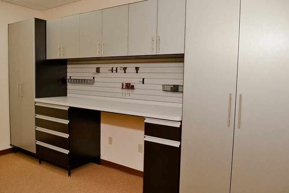 Part of a garage storage system with hanging tools and grey cabinets 