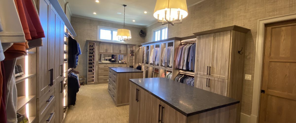 A luxury walk-in closet system with a light grey wash color scheme