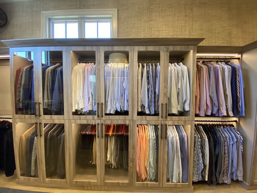 Rows of men's shirts in a luxury walk-in closet system with grey cabinet faces