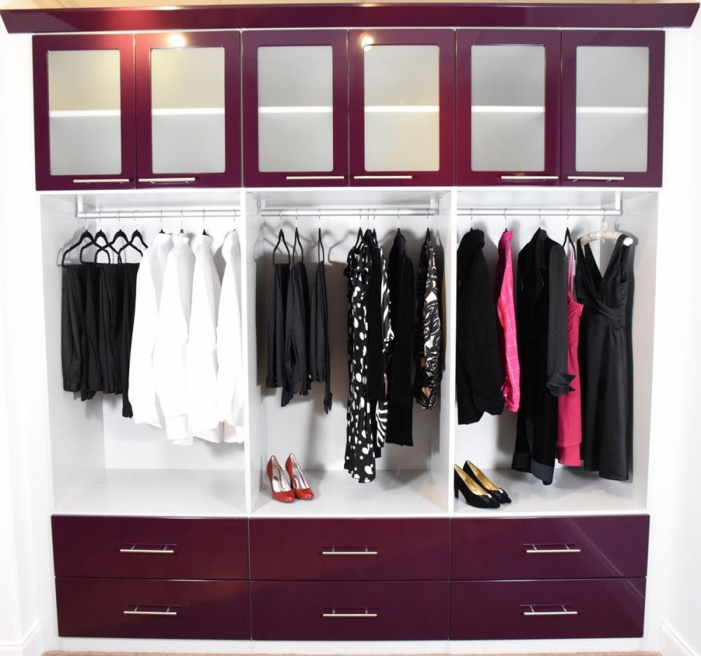 A modern closet system with drawers and hanging racks has a rich purple color.