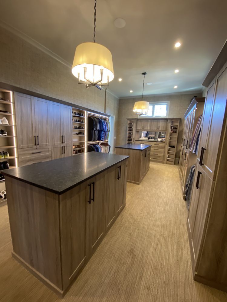 A custom walk-in closet system featuring shoe racks, rows of dress shirts, and dresser drawers 