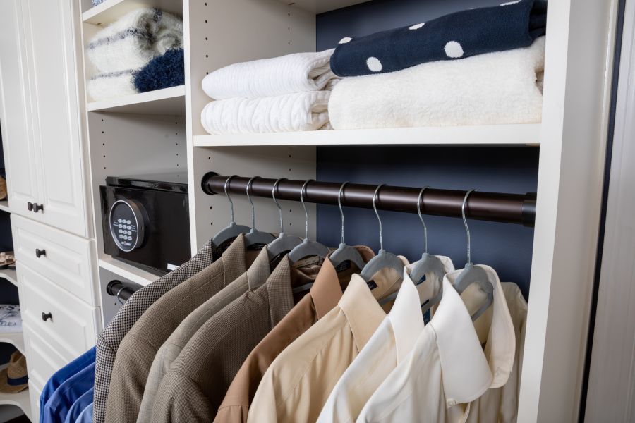 A close up image of a clothes rack filled with shirts inside of a master closet system.