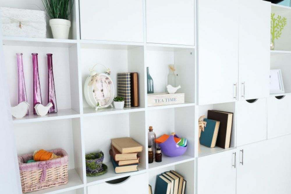 Part of a custom walk-in closet system featuring white cabinets and shelves holding odds and ends 