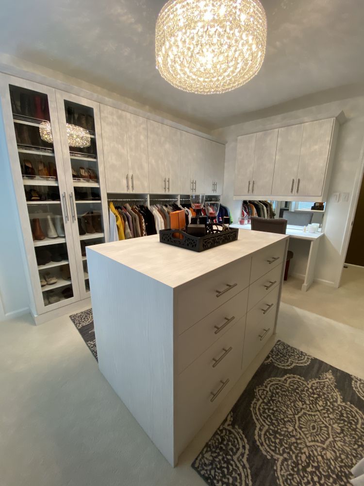 A beautiful walk-in closet system with a decorative light fixture and a neutral color scheme