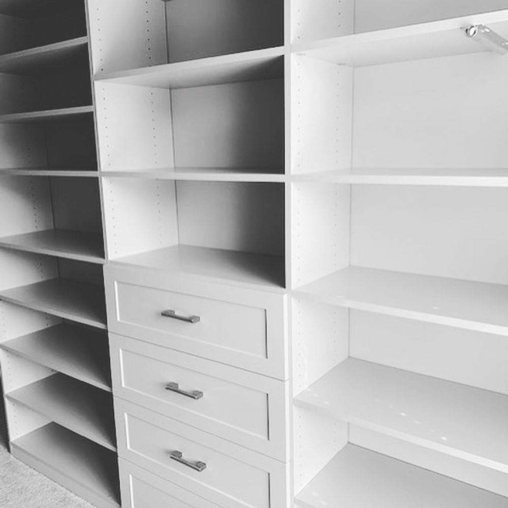 Part of closet system with light grey cabinet faces, shelves, and drawers 