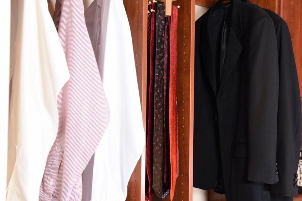 A close-up image of dress shirts on a hanging rack in a master closet system.