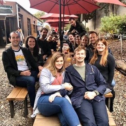 Group of alums sitting at a picnic table outside a brewery