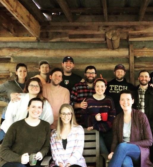 Group of Berry alums pose together outside a log cabin
