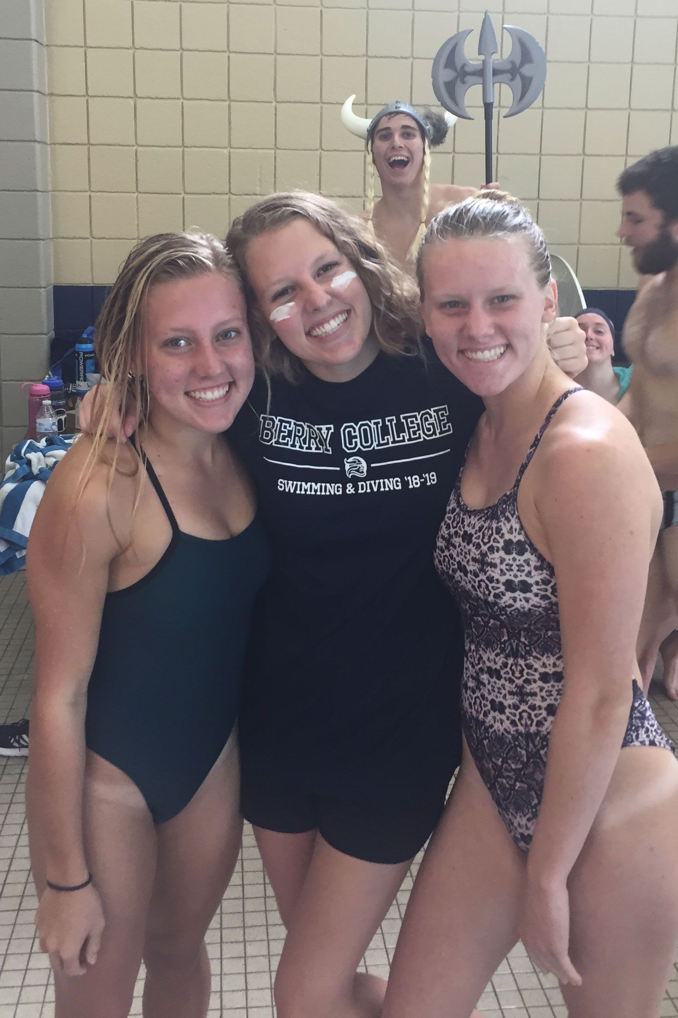 Three Berry students wearing swimsuits smile at a swim meet.