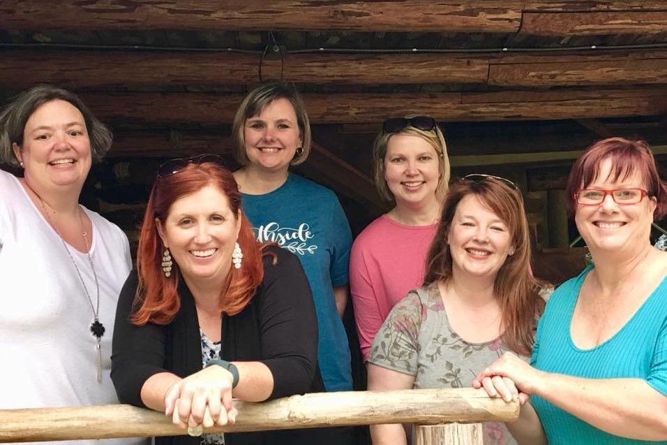 Group of Berry alumnae pose in front of log cabin