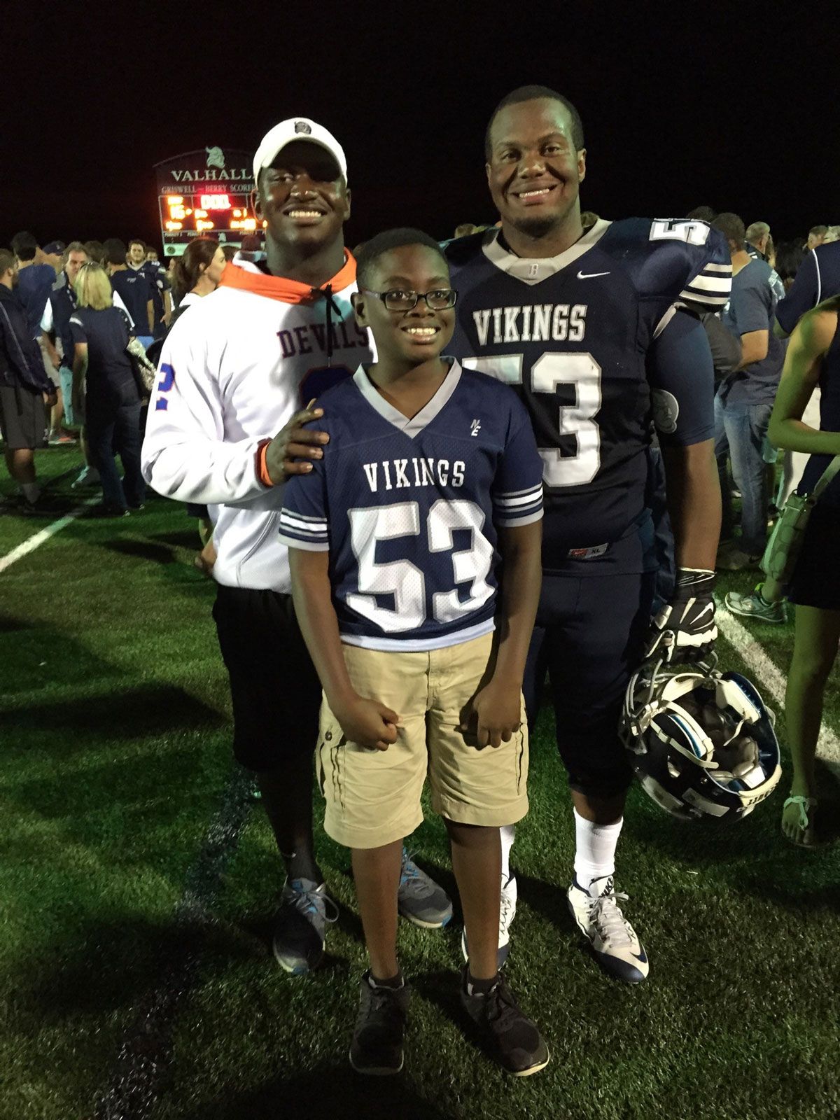 Three brothers stand together on a football 