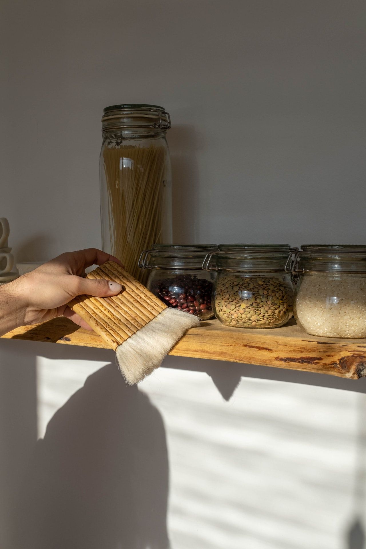 woman cleaning pantry shelf with a brush