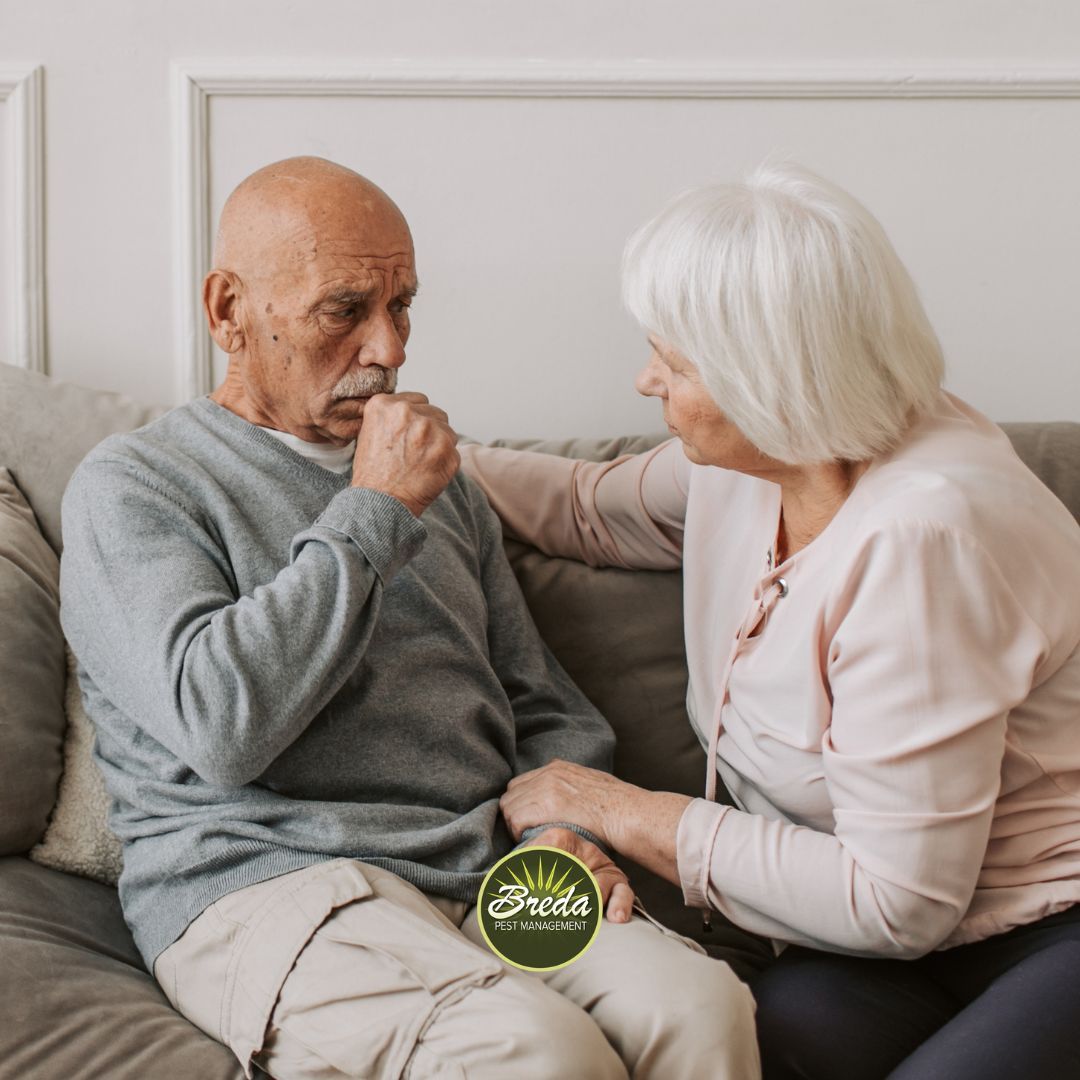 man and a woman sitting on a couch coughing