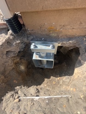 Uderpinning bracket on helical pile stabilizing townhome