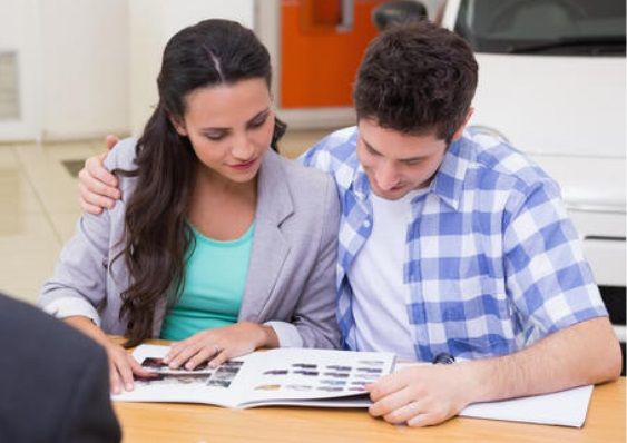 A young couple review a printed brochure at a car dealership