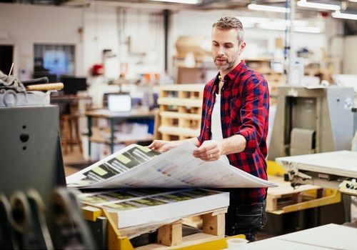 A printing plant worker moving some large printed sheets