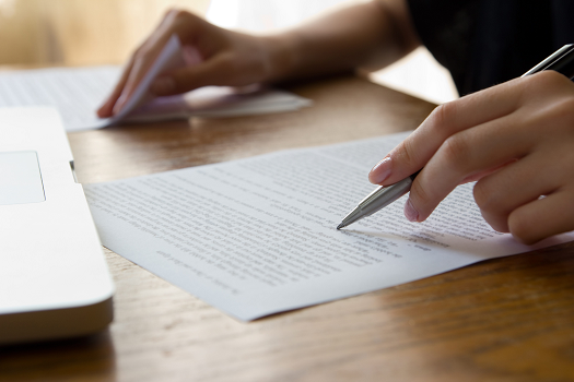 A person proofreading a document that is lying on a table
