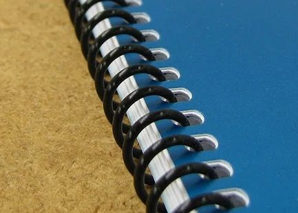 Close-up of a black spiral binding coil on a book with a blue cover