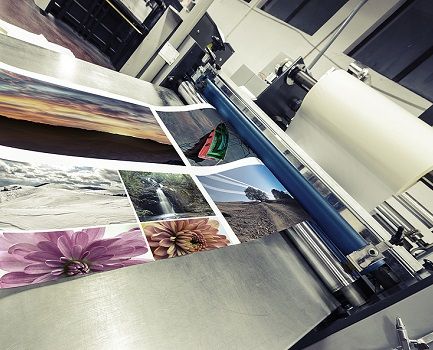 A commercial laminator applying a laminate to a colorful sheet