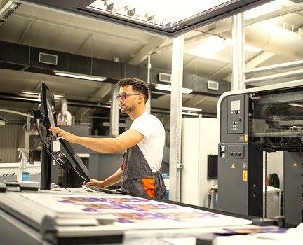 An Offset press operator reviewing press settings on a monitor